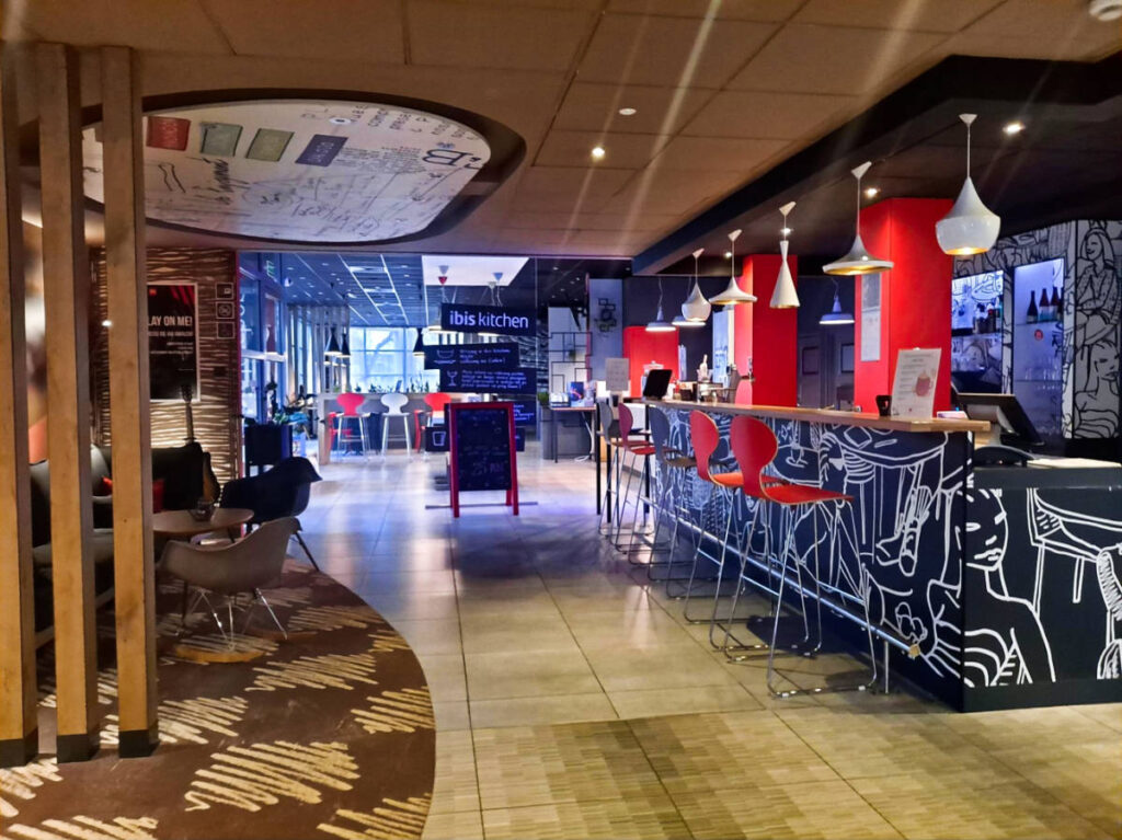 A cozy restaurant with a central bar and seating area inside Ibis Poznań Stare Miasto