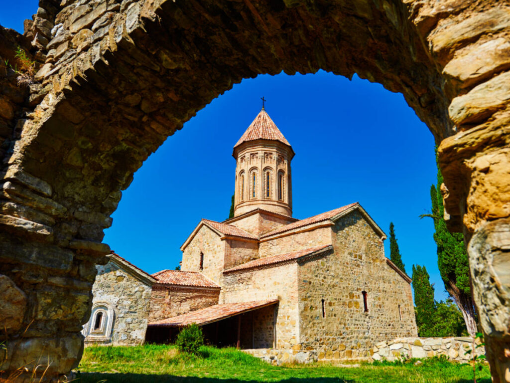 Exterior view of the Ikalto Monastery from the stone arch on a sunny day