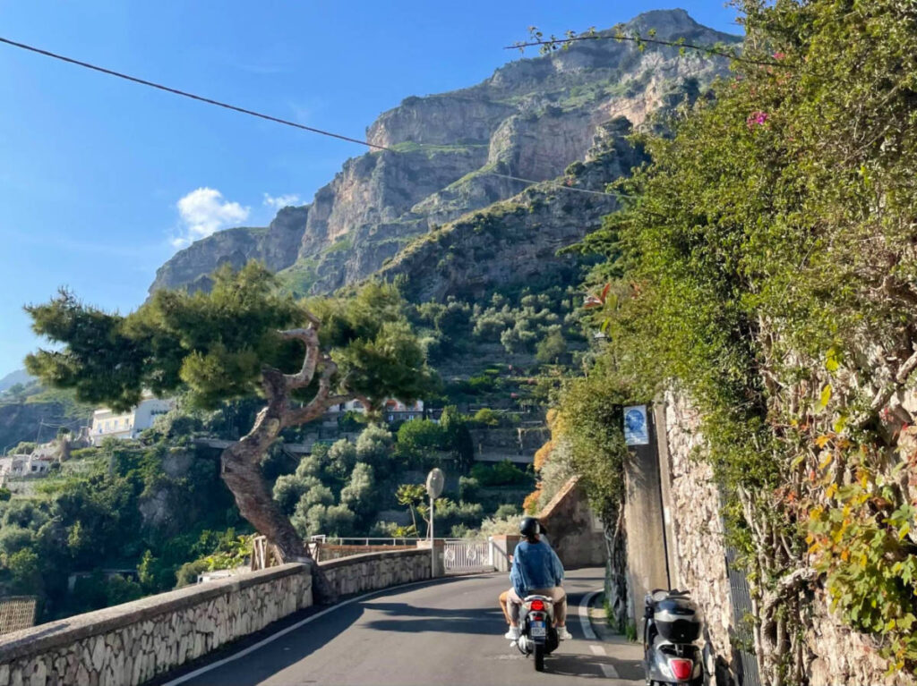 Person riding a motorcycle on a road amidst incredible scenery in Italy