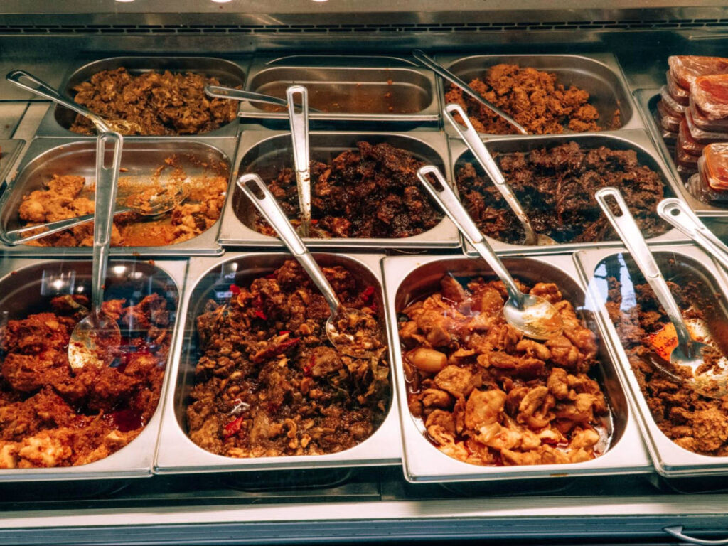 Food display case featuring an assortment of Indonesian dishes