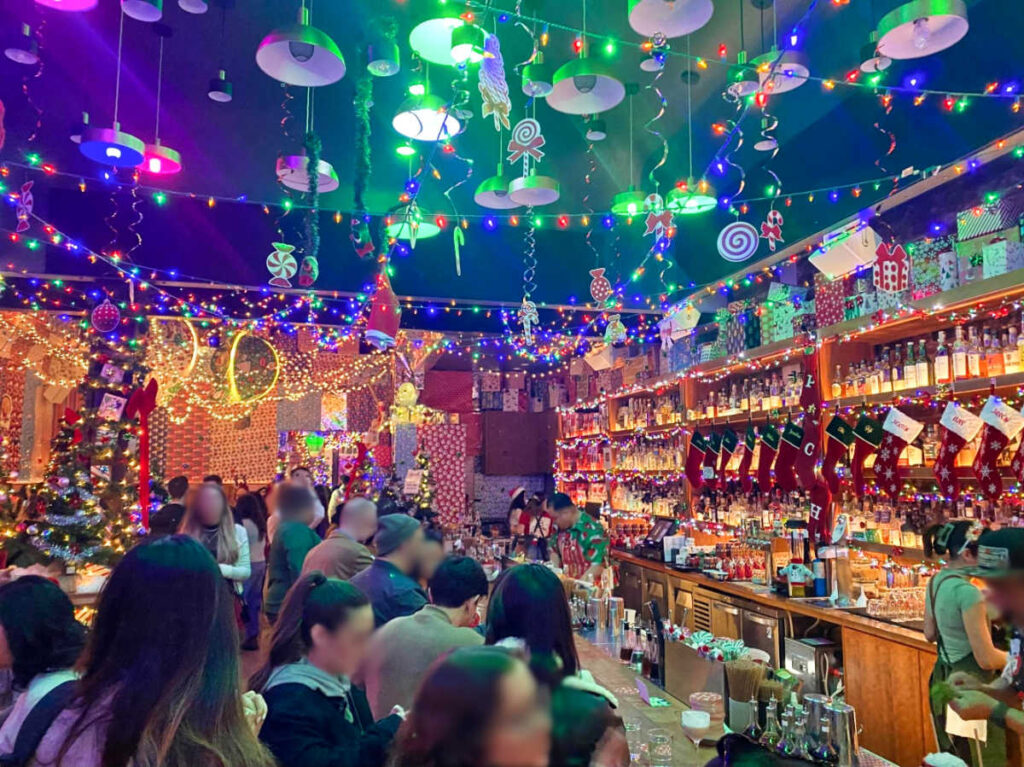 People drinking inside the Pacific Cocktail Haven with colorful holiday decorations around