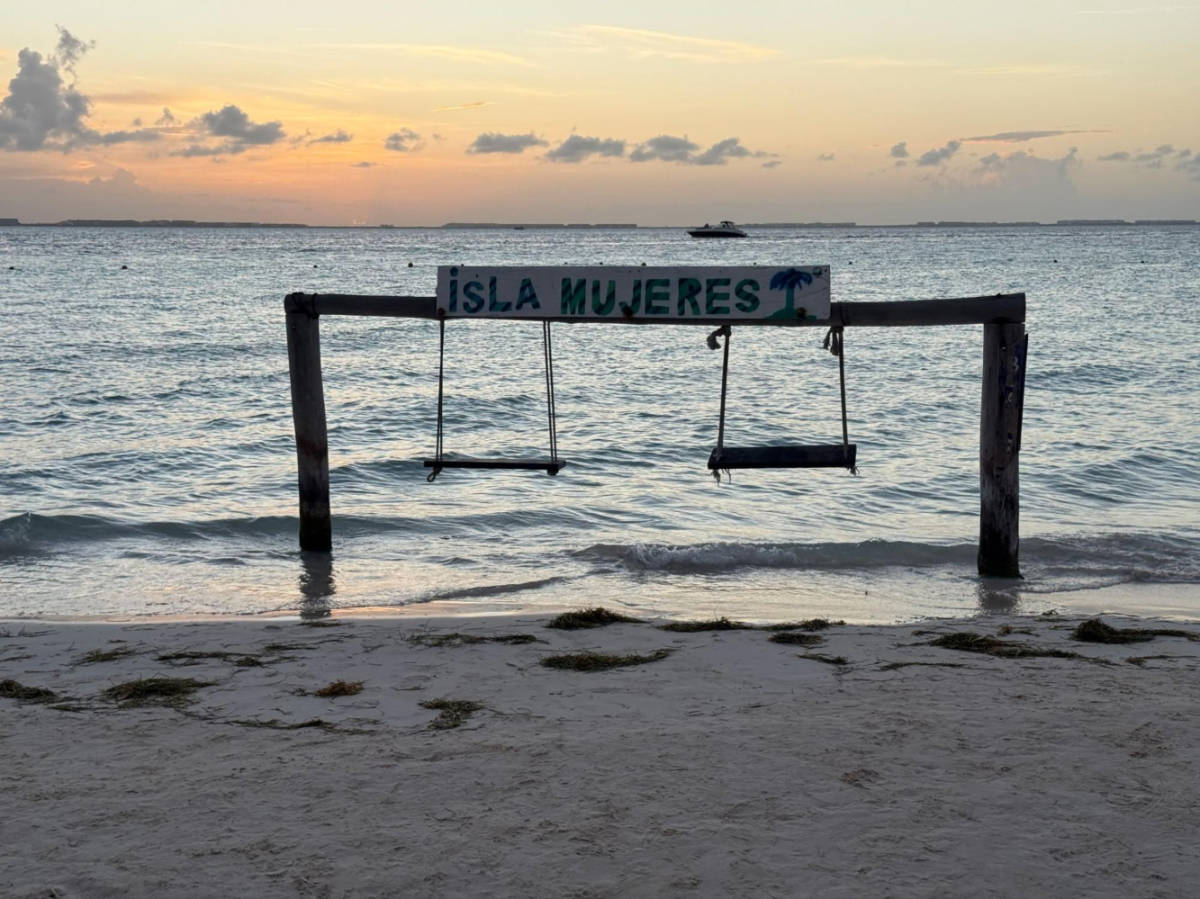 The Isla Mujeres sign above the swings in Isla Mujeres at sunset