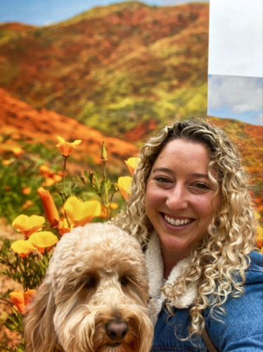 The author Jess Levy and her dog, posing with the field of poppies in the background
