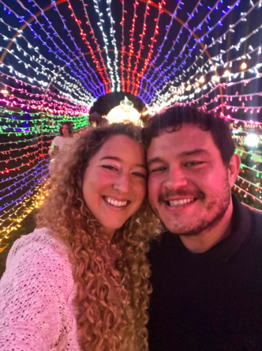 Travel Lemming author Jess and her date, smiling for a photo at the seasonal light tunnel at Lakehouse Resort