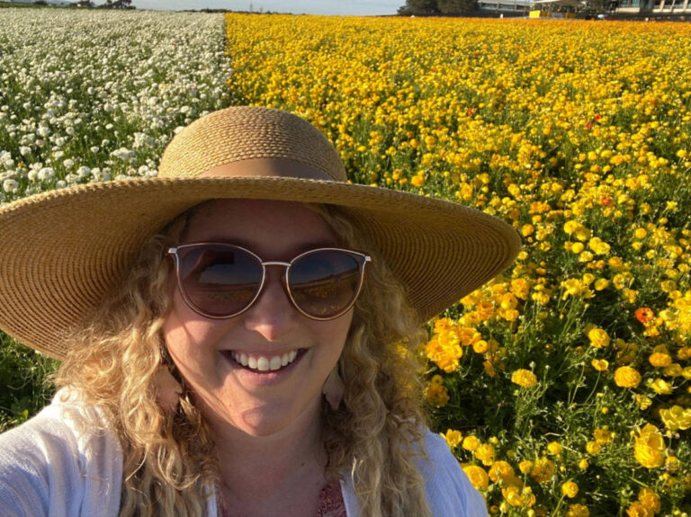 The author Jess Levy smiling for a photo with the vast flower field in the background