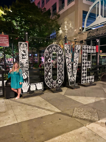 The author Jess Levy posing for a photo in front of a LOVE sign at the State Capitol
