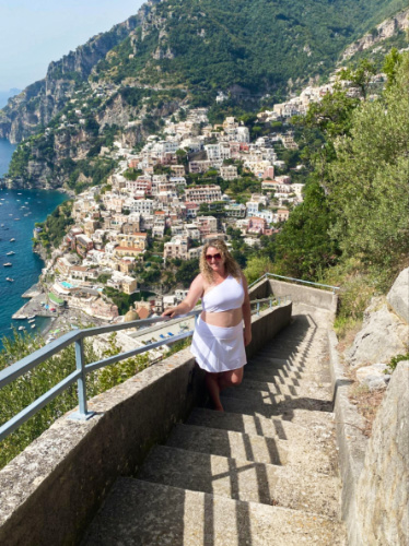 The author Jess Levy posing for a photo with an overlooking view of Amalfi Coast