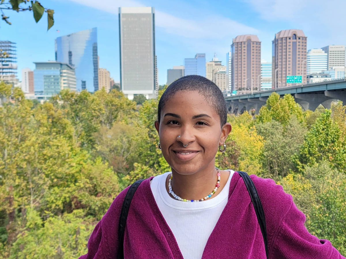 The author, Jonaye Barnum, smiling for a photo with the view of Downtown Richmond from Floodwall Park