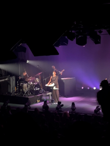 Joy Crookes performing on the stage with a band