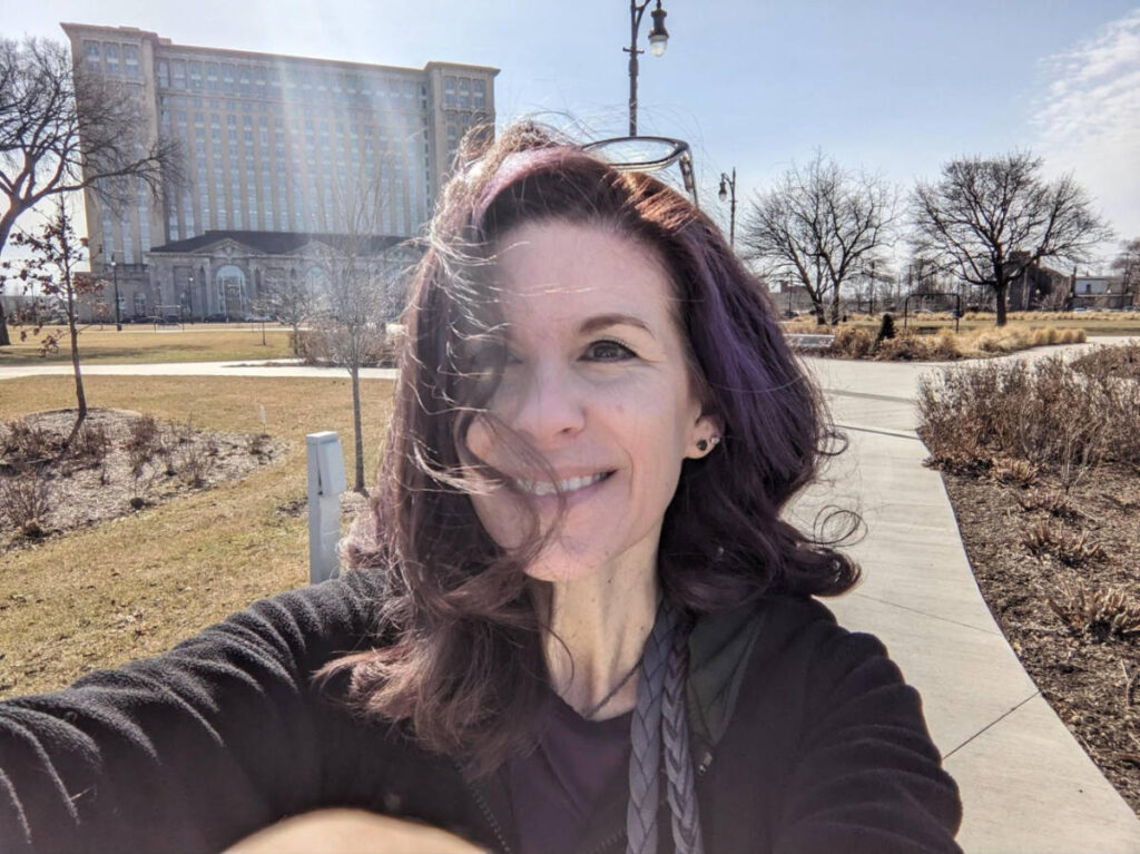 The author Julie Ballantyne Brown, smiling in front of the grand facade of Michigan Central
