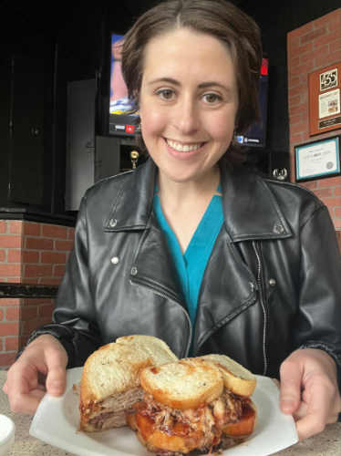 The author Kara Walters holding a plate with pulled pork sandwich at LC’s Bar-B-Q