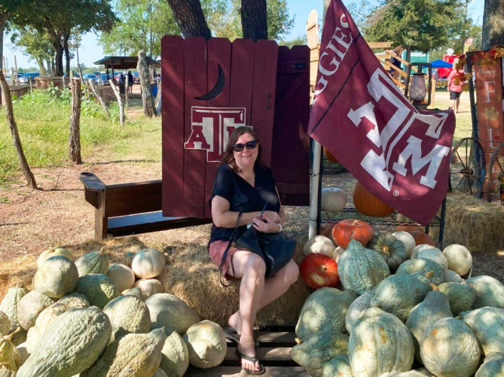 The author Karen Smith sitting at the pumpkin patch displays