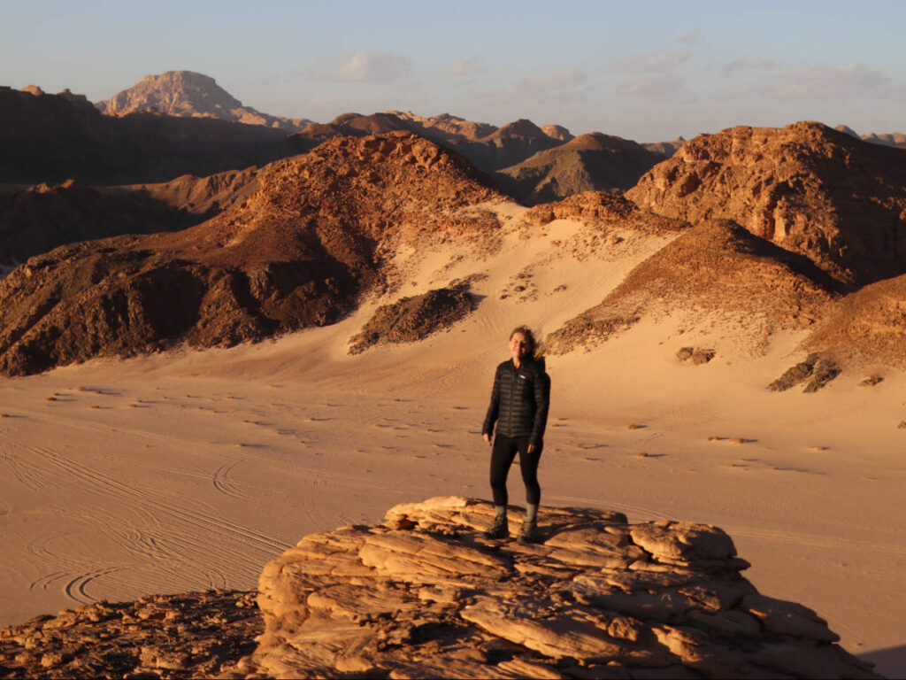 The author Kate McMahon, standing on top of a rock on a deserted place in Egypt