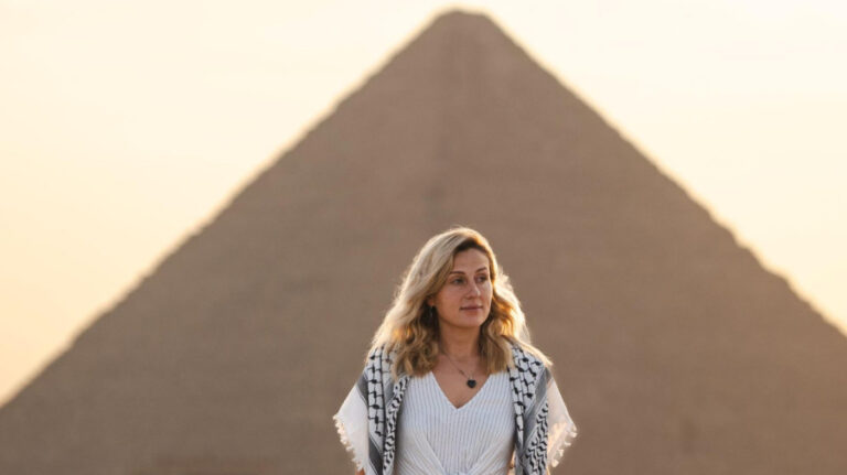 The author Kate McMahon, standing with a view of the Pyramids of Giza