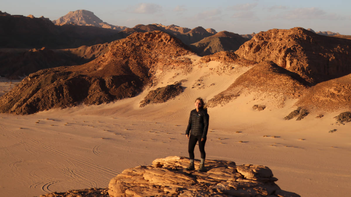 The author Kate McMahon, standing on top of a rock on a deserted place in Egypt