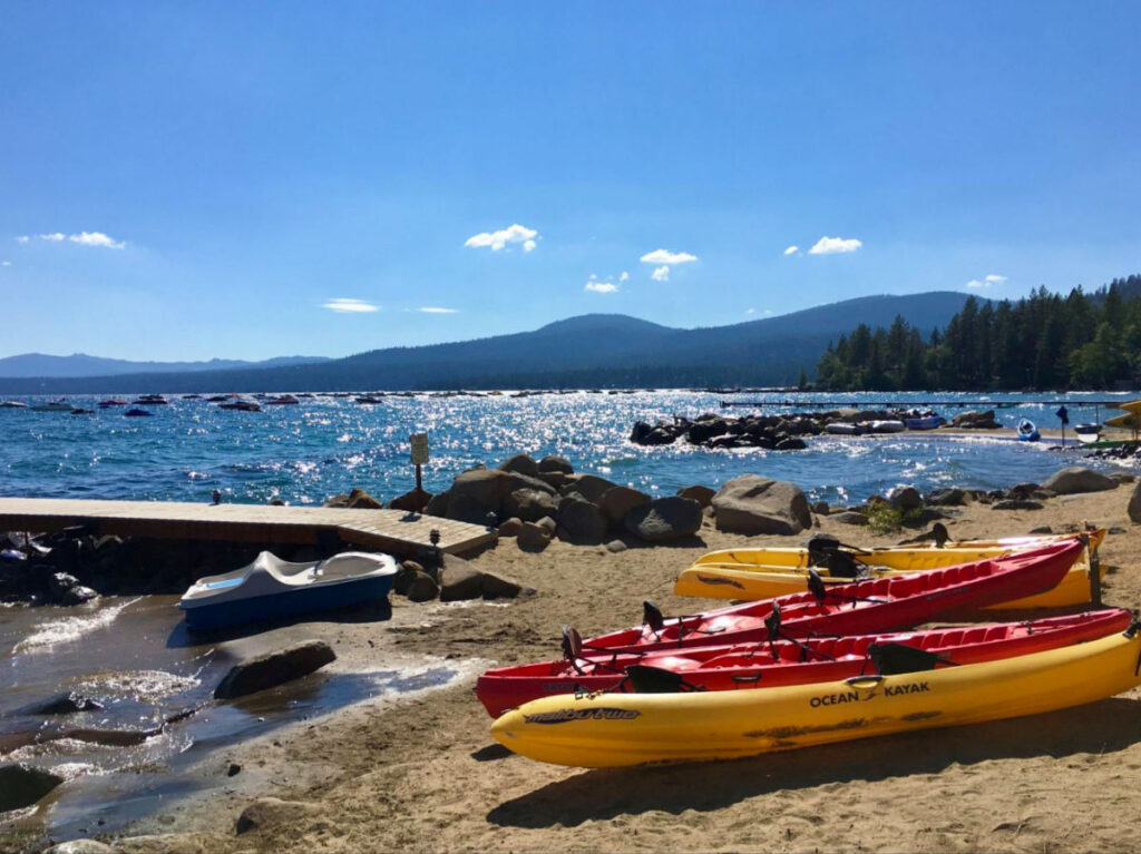 Kayaks lined up on the sandy beach at Lake Tahoe in Kings Beach