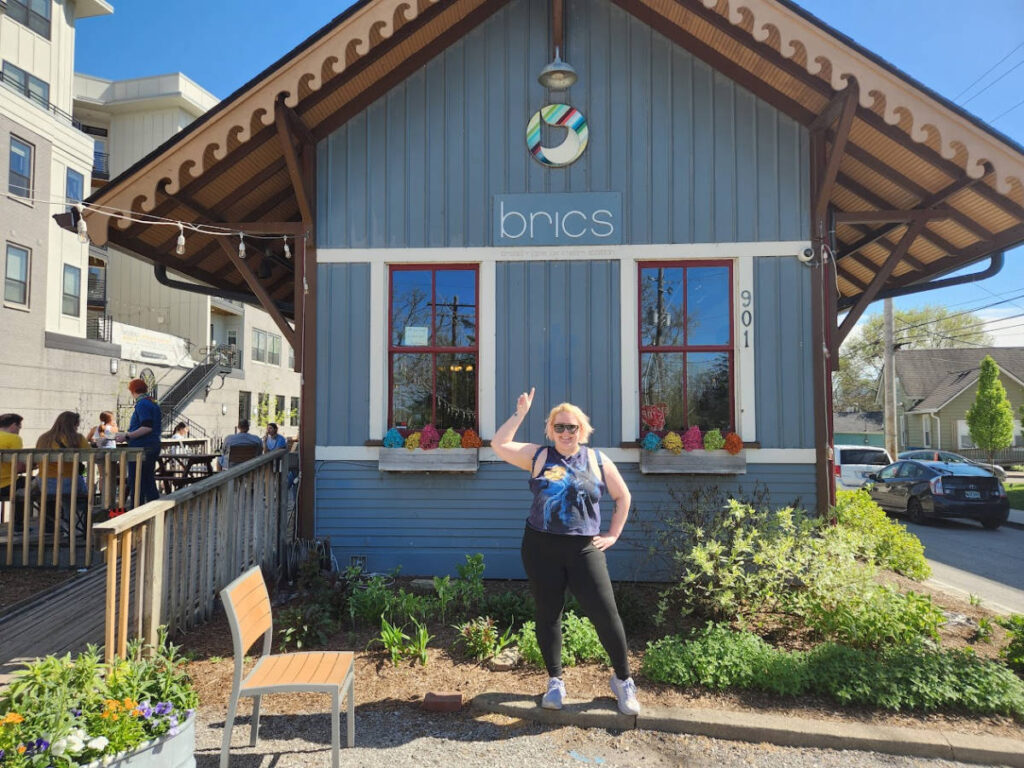 The author Kelsey Nighthawk posing for a photo outside the BRICS