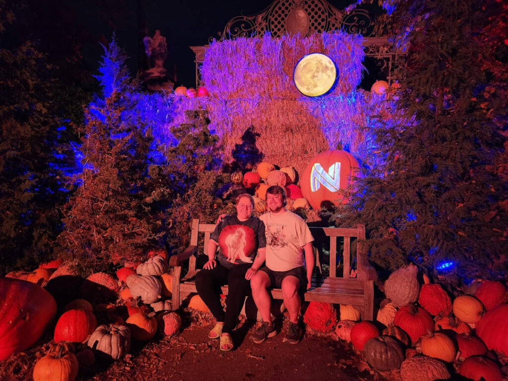 The author Kelsey Nighthawk and her husband sitting near the Halloween displays at the Newfields