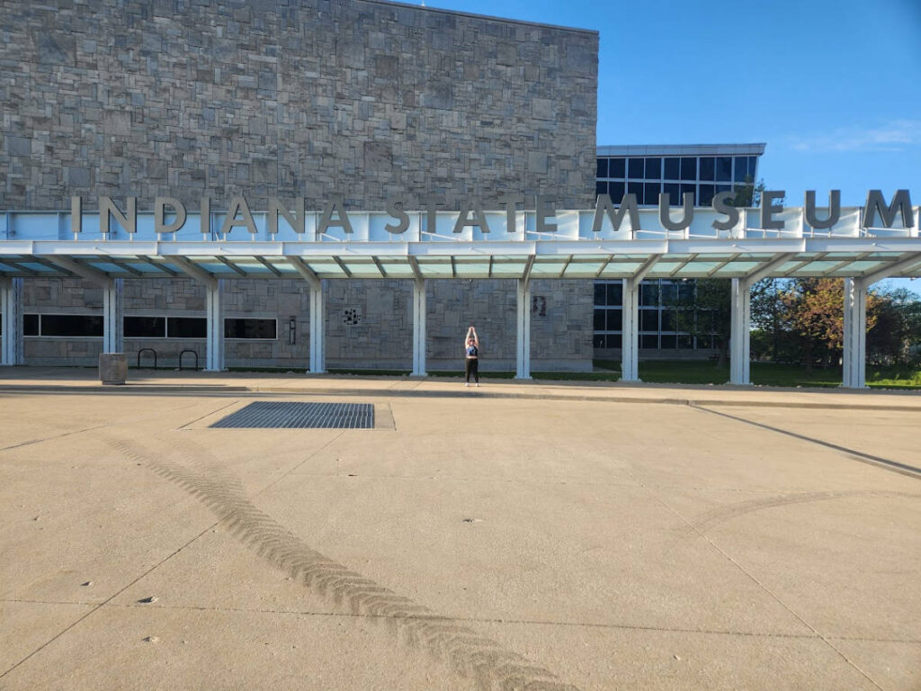 The author Kelsey Nighthawk posing for a photo at the entryway of Indiana State Museum