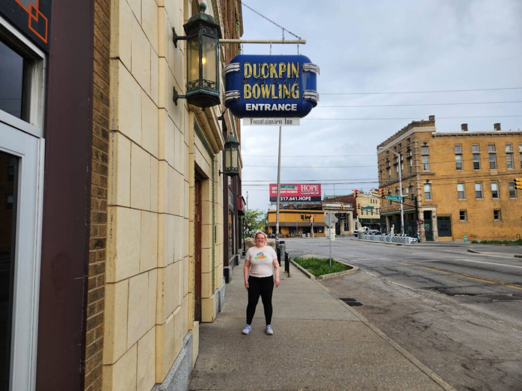 The author Kelsey Nighthawk standing near the signage outside the Atomic Bowl Duckpin Bowling