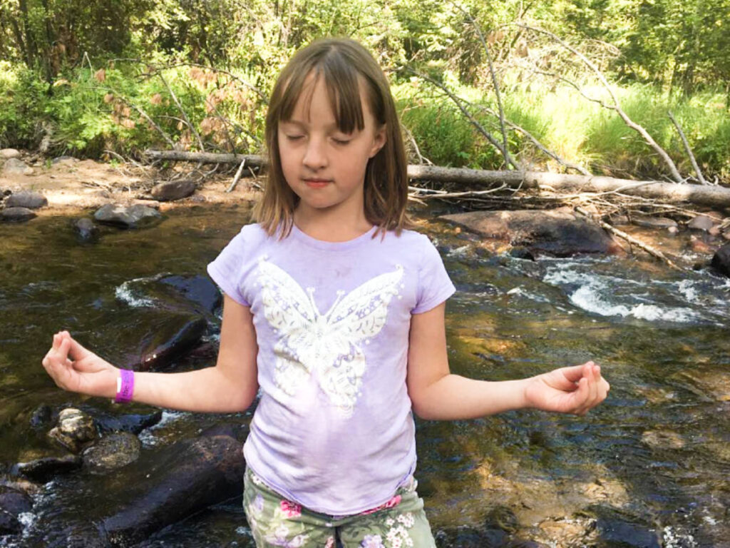 A child meditating on the streaming water