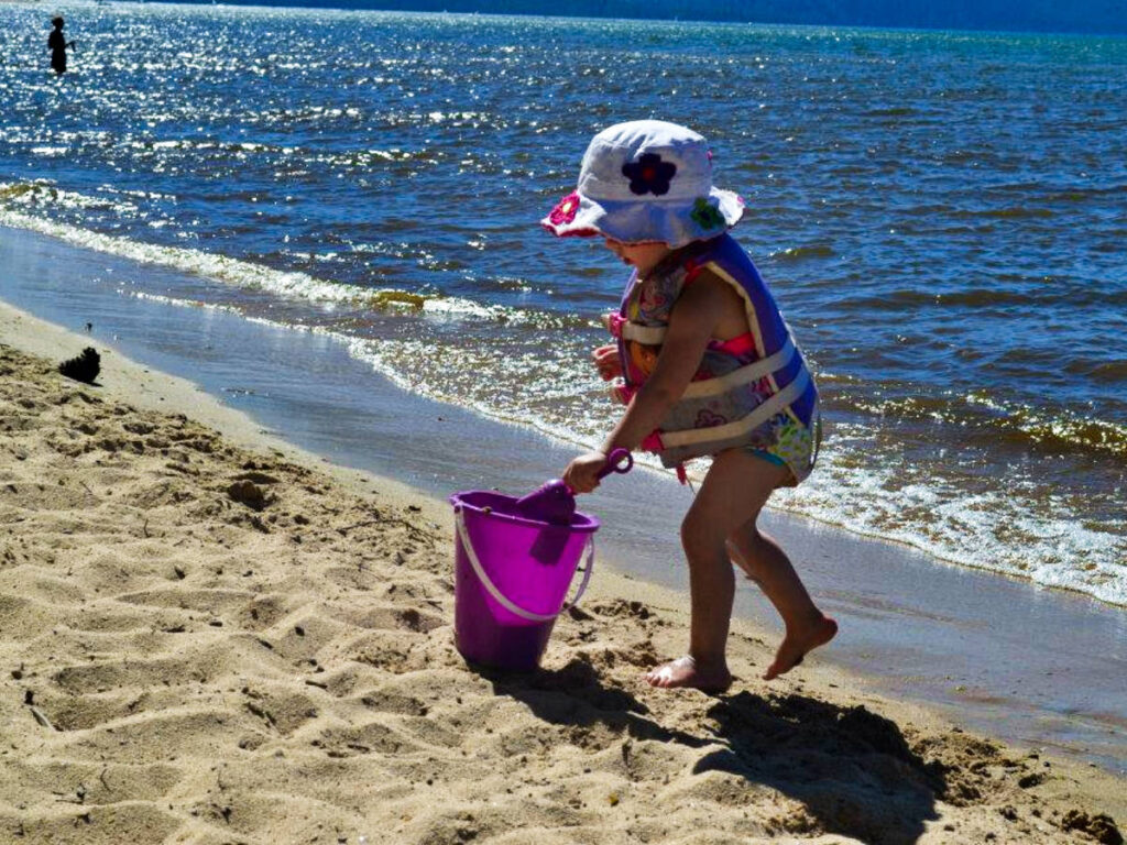A little kid playing on the sand at the beach