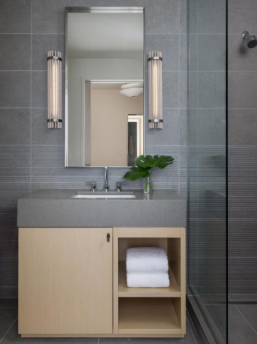 A mirror and sink on a bathroom in Kimpton Claret Hotel