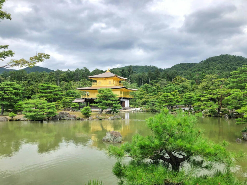 View of the Kinkakuji surrounded by greenery reflecting on the pond