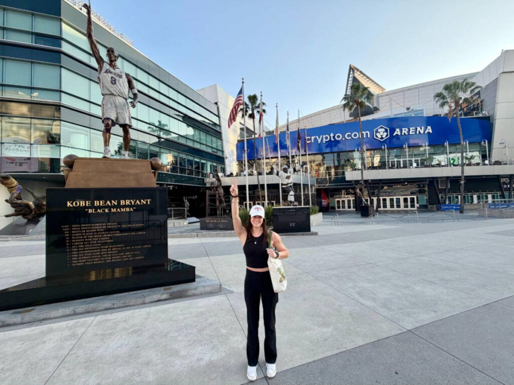 The author Betty Hurd, posing for a photo with Kobe's statue in front of Crypto Arena