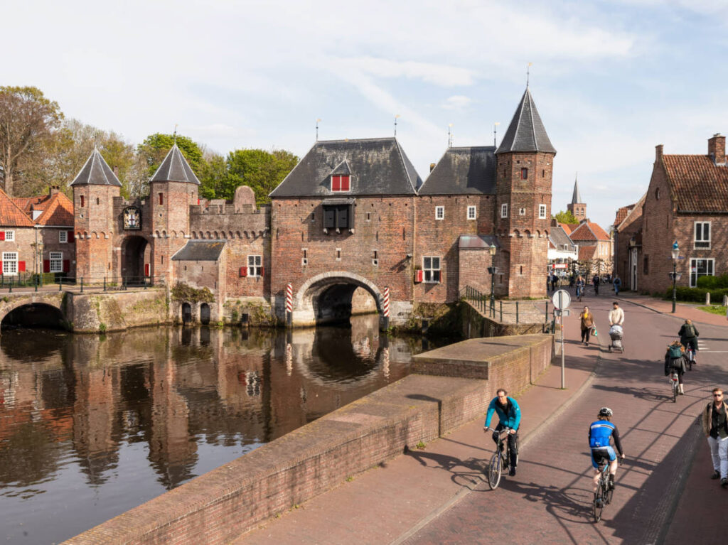 People walking and cycling along the historic street and waterpoort de Koppelpoort