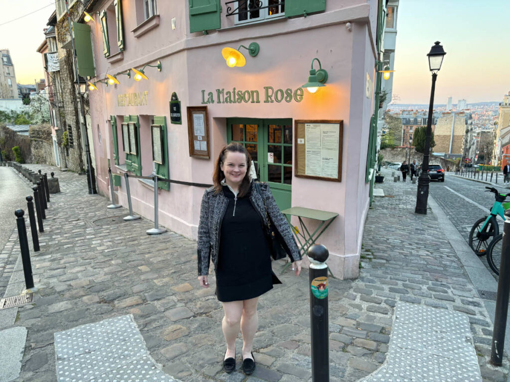The author, Rachel Kapelke Dale smiling for a photo in front of La Maison Rose Restaurant