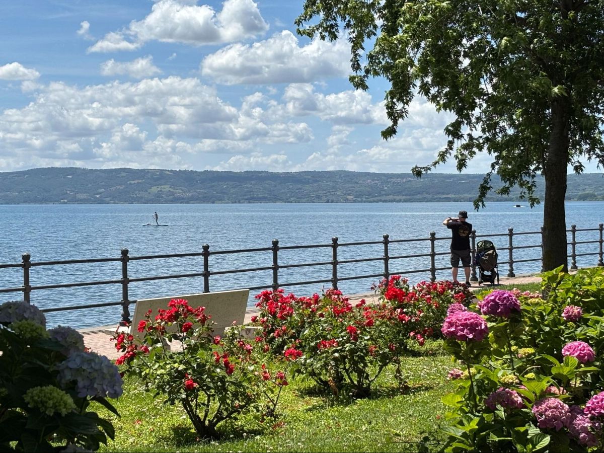 A man taking a picture of the views of Lake Bolsena from the walkway