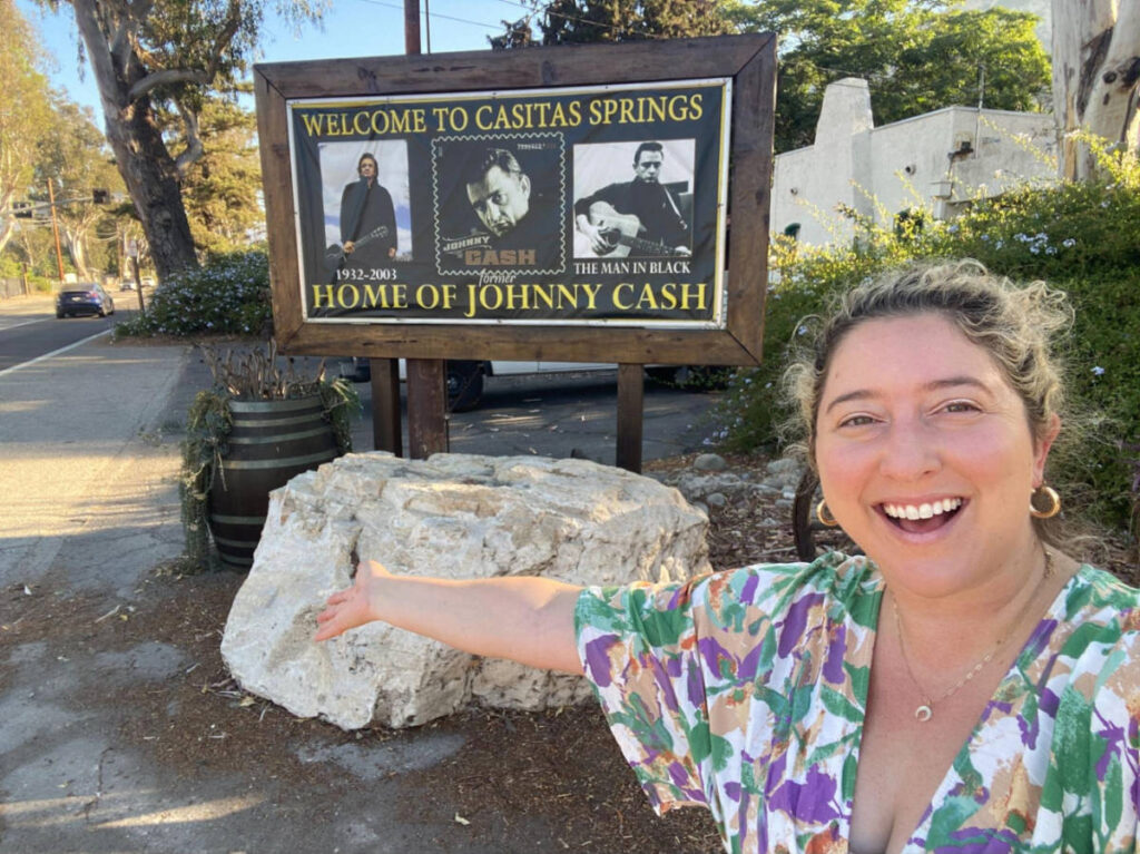 The author Jess Levy, smiling in front of the welcome signage of Lake Casitas
