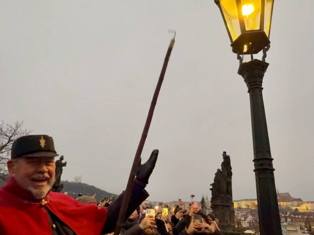 A man lighting the gas lamp at the Charles Bridge