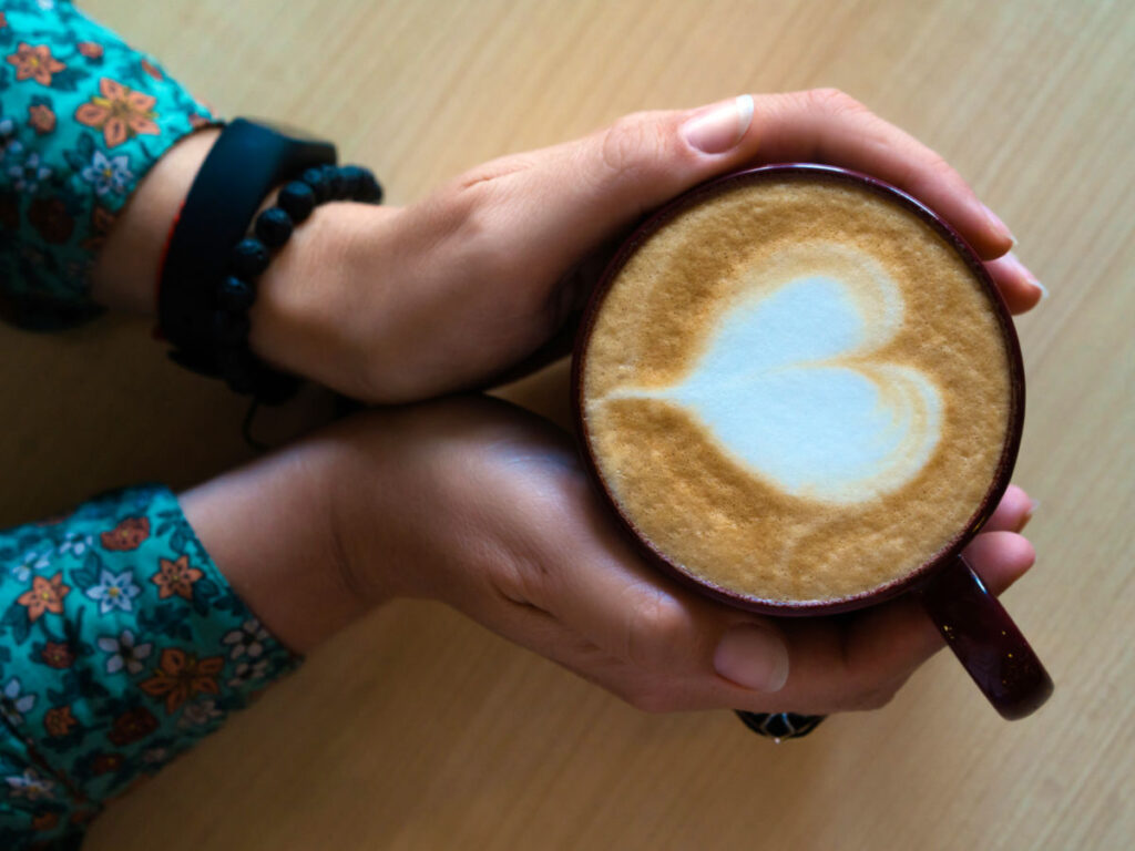 Hands holding a large mug of cappuccino with Heart-shaped latte art