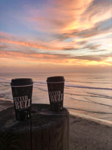Two cups of latte with a scenic view of the sunset over the beach