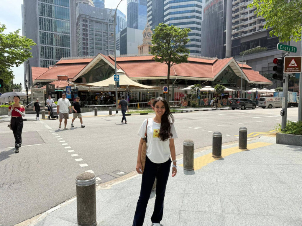 The author, Advaita smiling for a photo with the Lau Pa Sat on her background