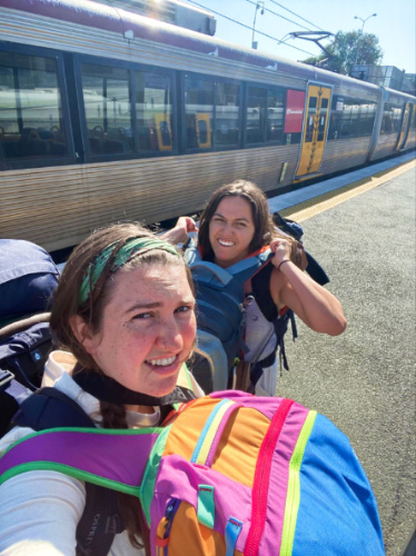 The author Laura McFarland and her partner carrying multiple backpacks on a sunny day