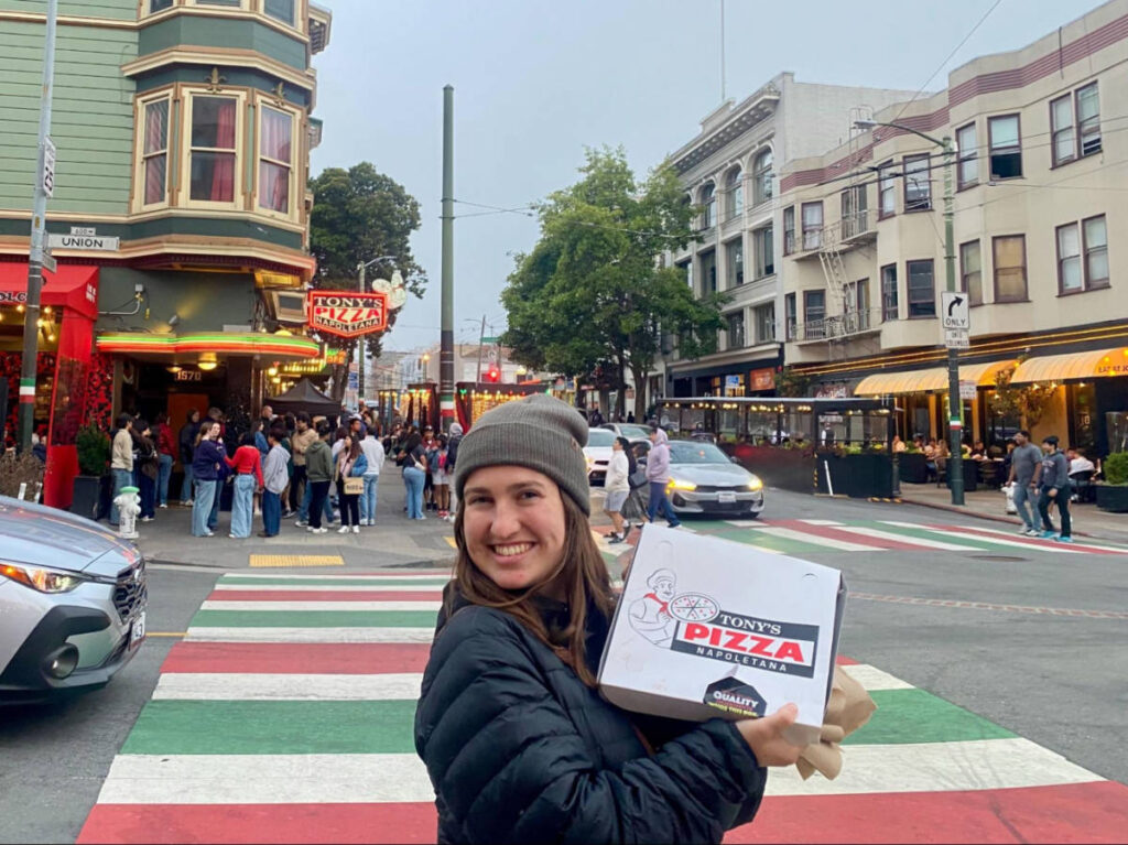 The author Laura McFarland showing a box of pizza in front of Tony's