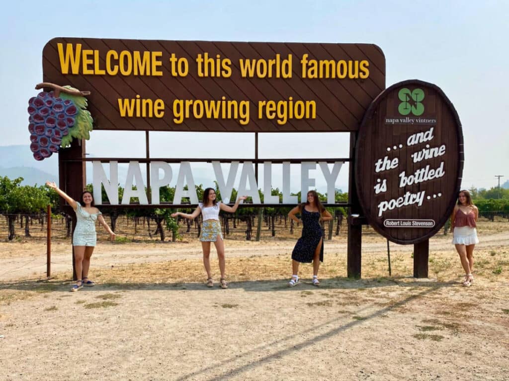 The author Laura McFarland's friends posing below the Welcome to Napa Valley signage