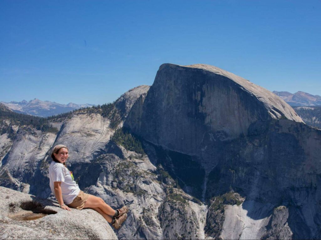 The author Laura McFarland sitting on a rock in front of the Half Dome