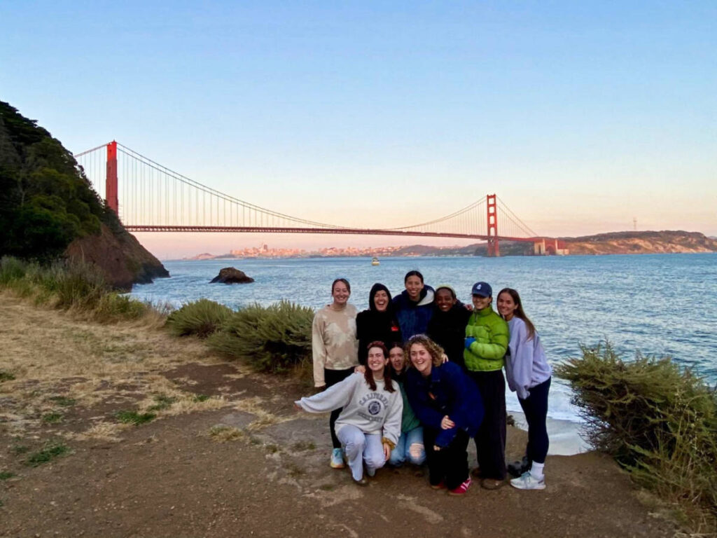 The author Laura McFarland and her friends smiling for a photo with the Golden Gate Bridge view at sunset