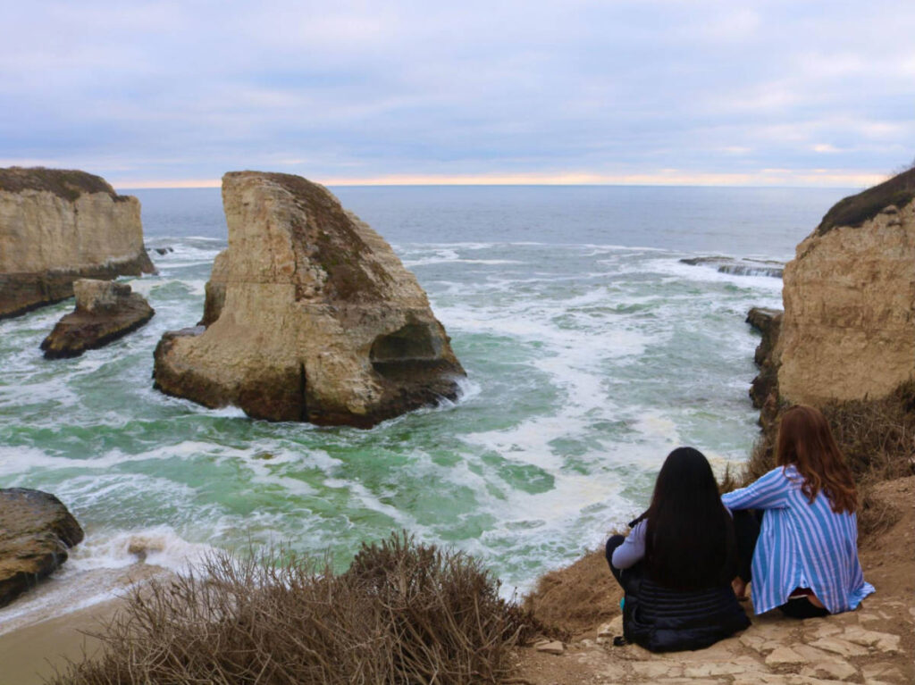 The author Laura McFarland and her friend sitting on the ground while admiring the Shark Fin Rock