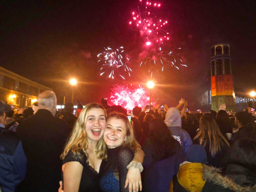 The author Laura and her friend posing for a photo at the San Francisco Embarcadero with the fireworks in the background
