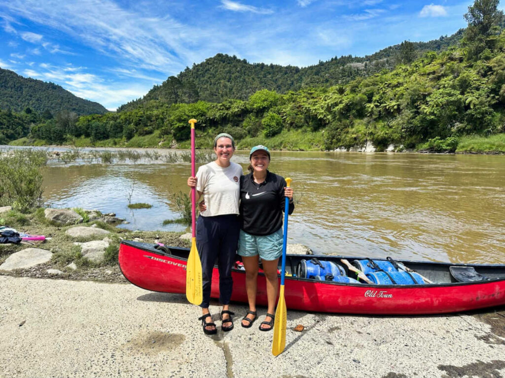 The author Laura McFarland and her partner holding their paddleboards near the river