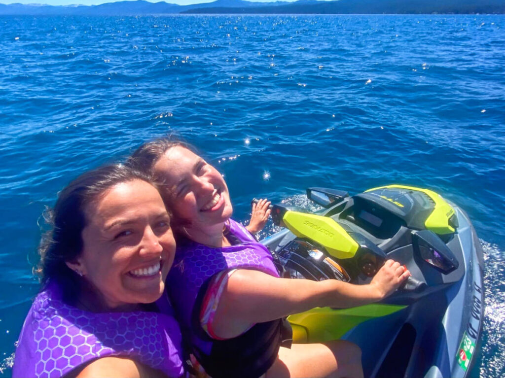 The author Laura McFarland and her partner, smiling for a photo while jet skiing on Lake Tahoe