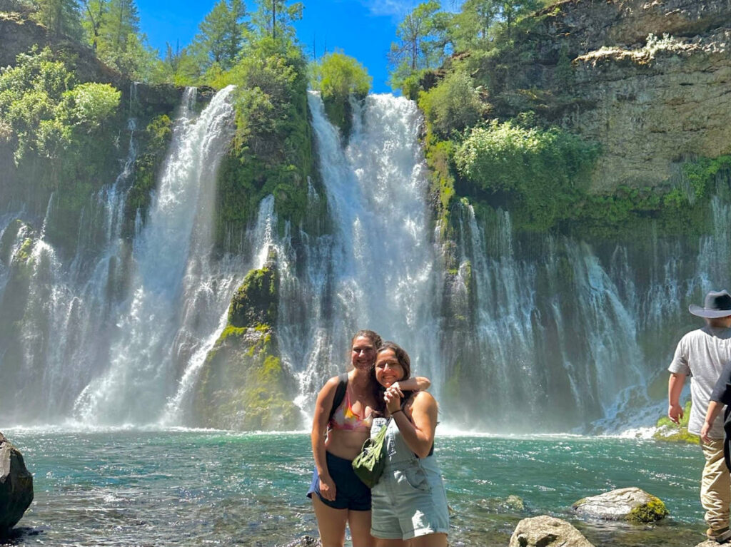 The author Laura McFarland and her partner posing for a photo in front of the Burney Falls