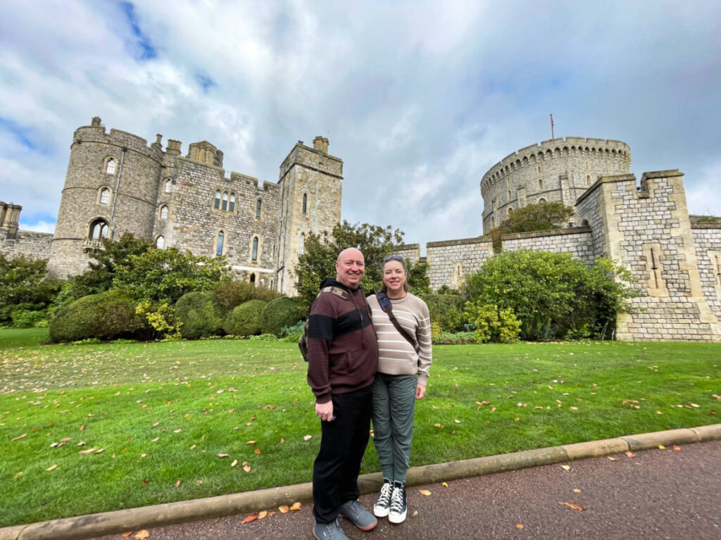 The author Laura and her husband posing for a photo in front of the Windsor Castle
