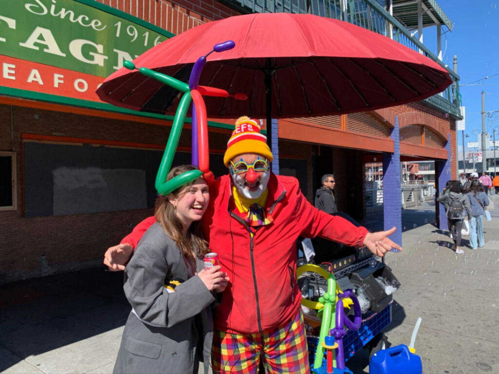 The author Laura McFarland, smiling with a street performer dressed as a clown at Pier 39