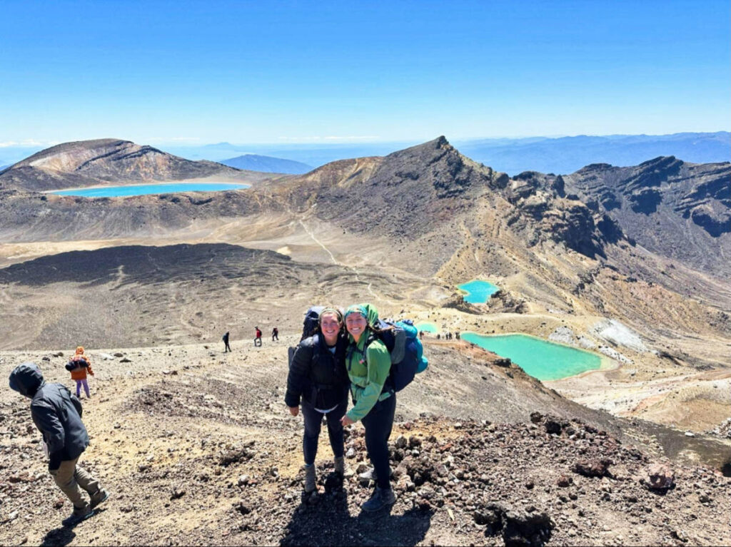 The author Laura McFarland and her partner with an overlooking view of the Emerald Lakes and Blue Lake in the background
